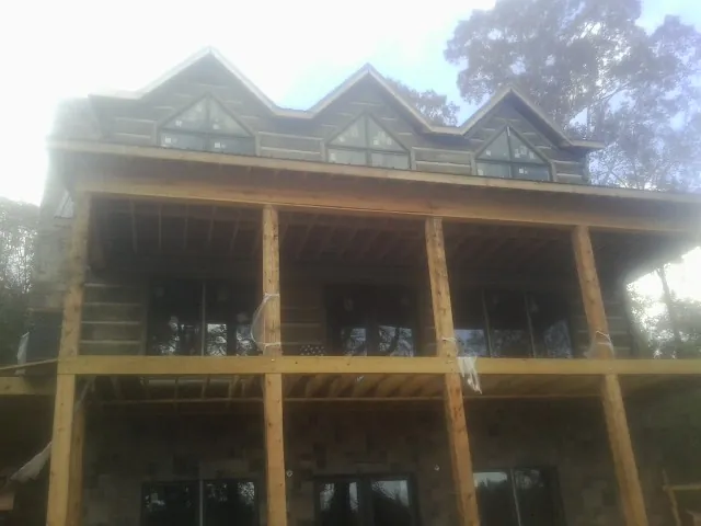 Dormers and porch framing on a large log home under construction — Roof Coating work by our crew in Donaldsonville
