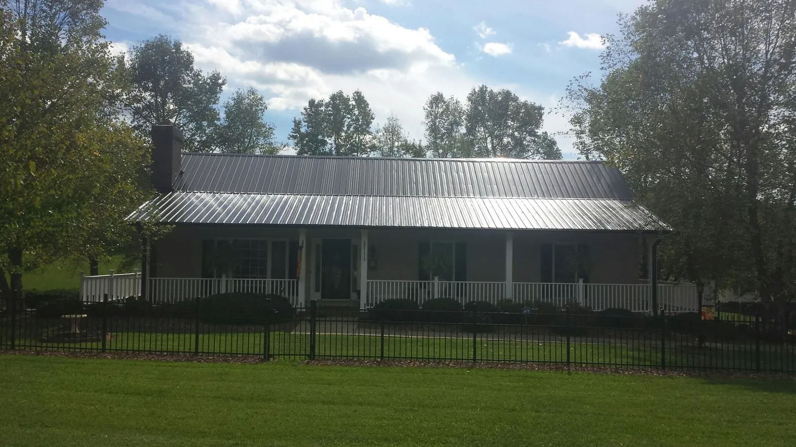 Gray metal roof on a brick ranch with a full width front porch — Gutter Guard Installation work by our crew in Donaldsonville
