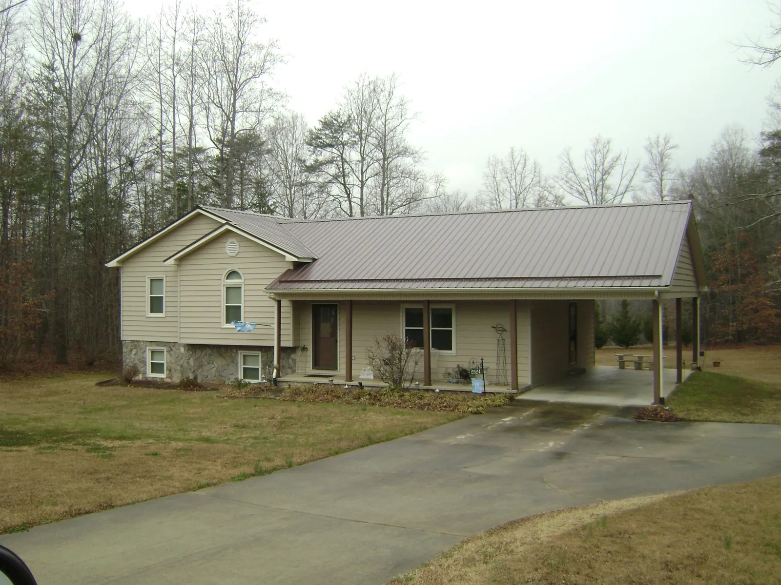 Brown metal roof on a tan split level home with an attached carport in Donaldsonville
