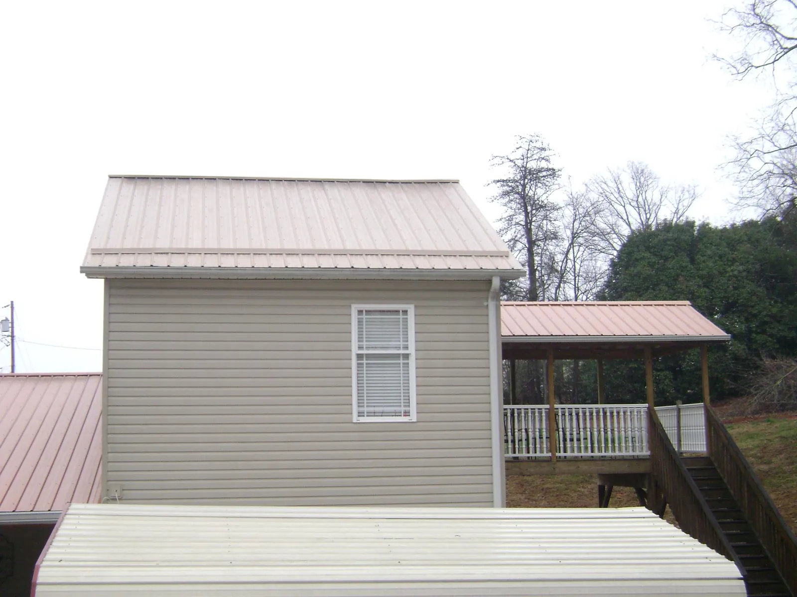 Tan metal roofs on a two story addition and attached porch, from a Roof Replacement job in Donaldsonville