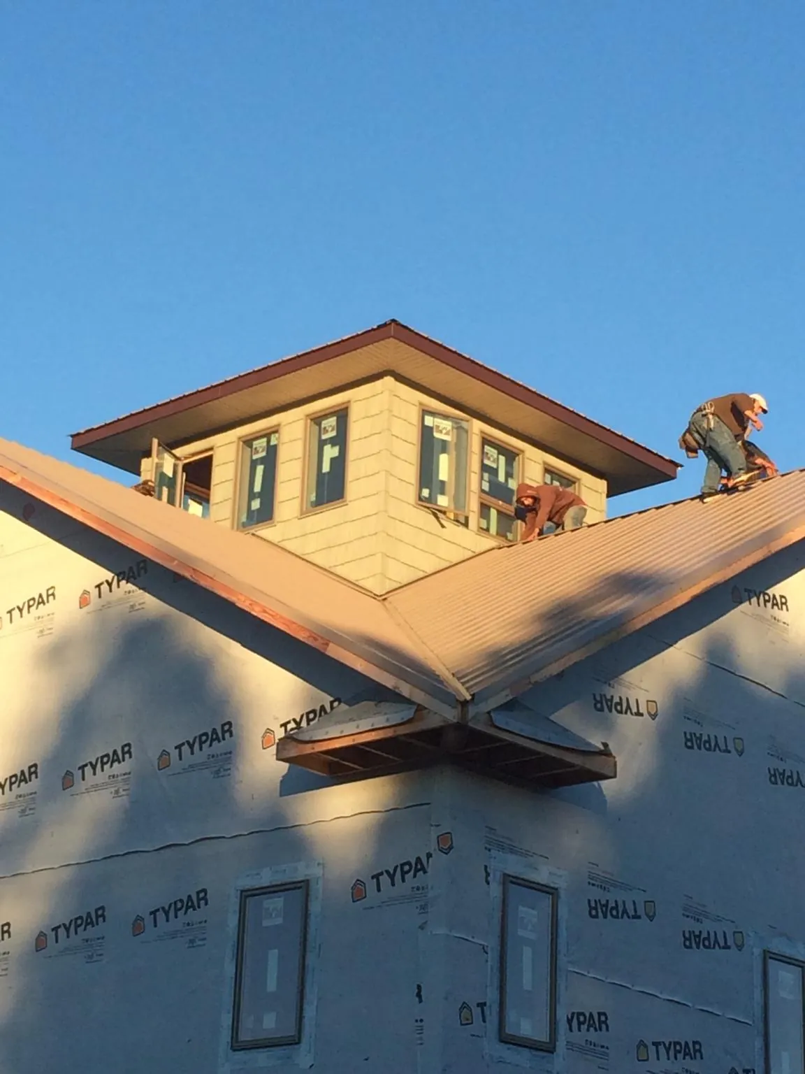 Roofers working around a rooftop cupola on a new metal roof at sunset — Roof Waterproofing in Donaldsonville by Roofing Brothers